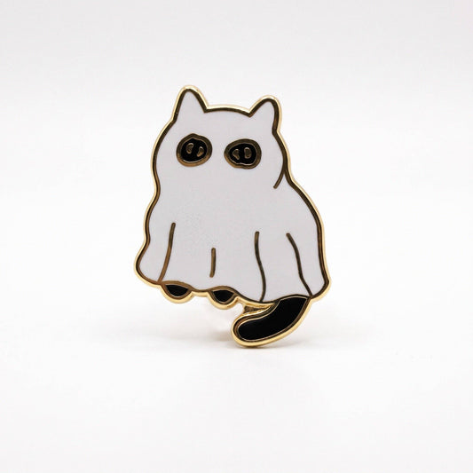 Gold-plated hard enamel pin of a cat wearing a white ghost sheet with black eyes and a tail.