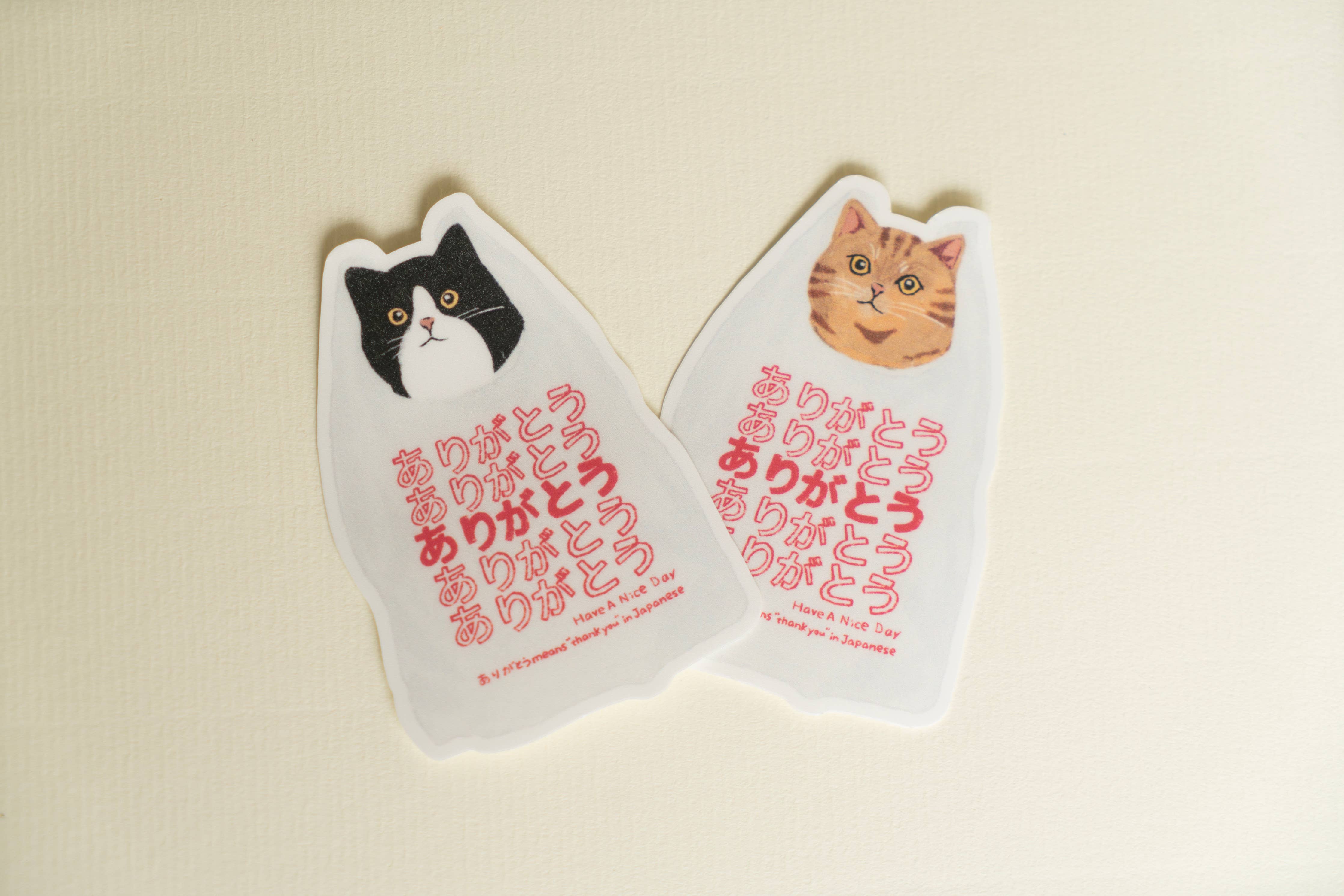 Set of two “Arigatou” cat thank you stickers with black/white and orange tabby cat illustrations.