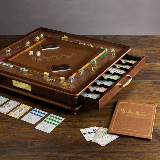 Monopoly Luxury Edition board game with gold tokens, cards, and a piece drawer on a wooden table.