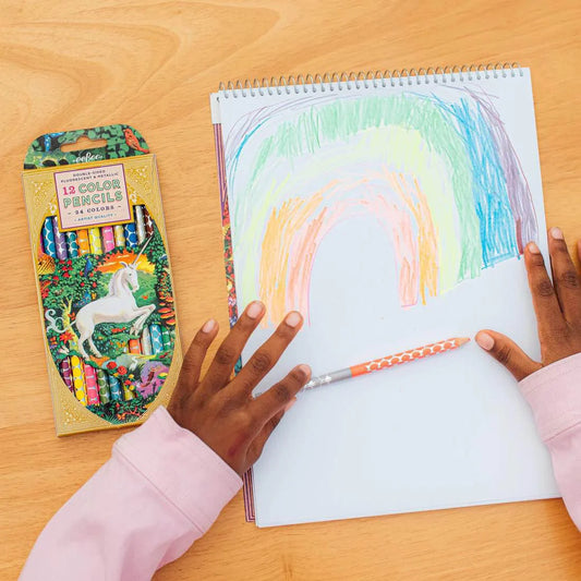 Unicorn Garden 12 Double Color Pencils used by a child to draw on a sketchpad at a wooden table.