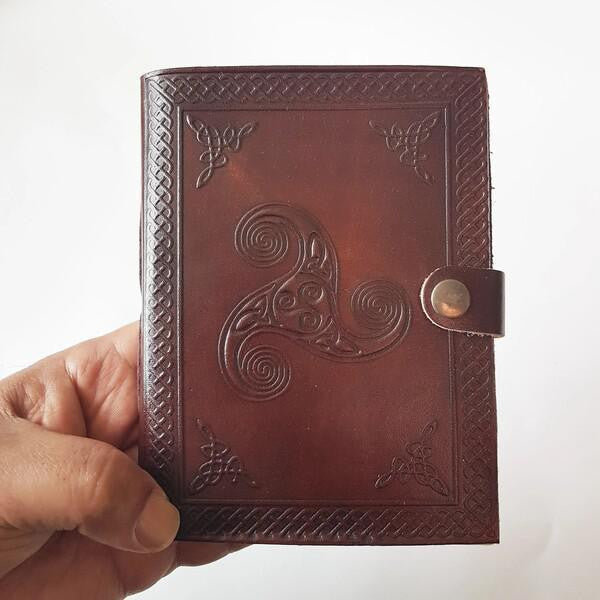 Leather Notebook (QTY-3) with embossed Celtic designs and button clasp held in a hand.