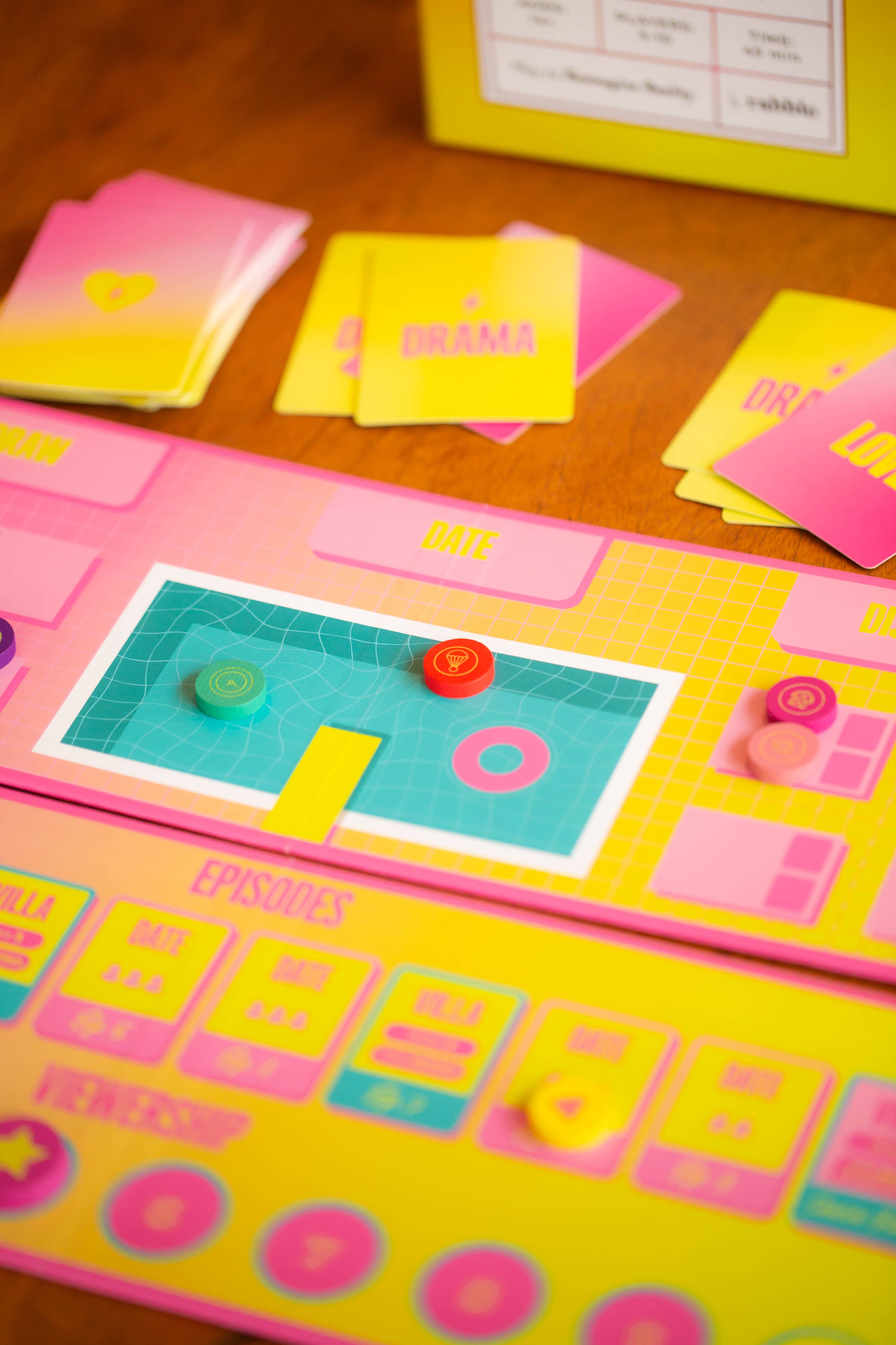 Lovestruck party board game with pink and yellow cards, tokens, and pool graphic on a wooden table.