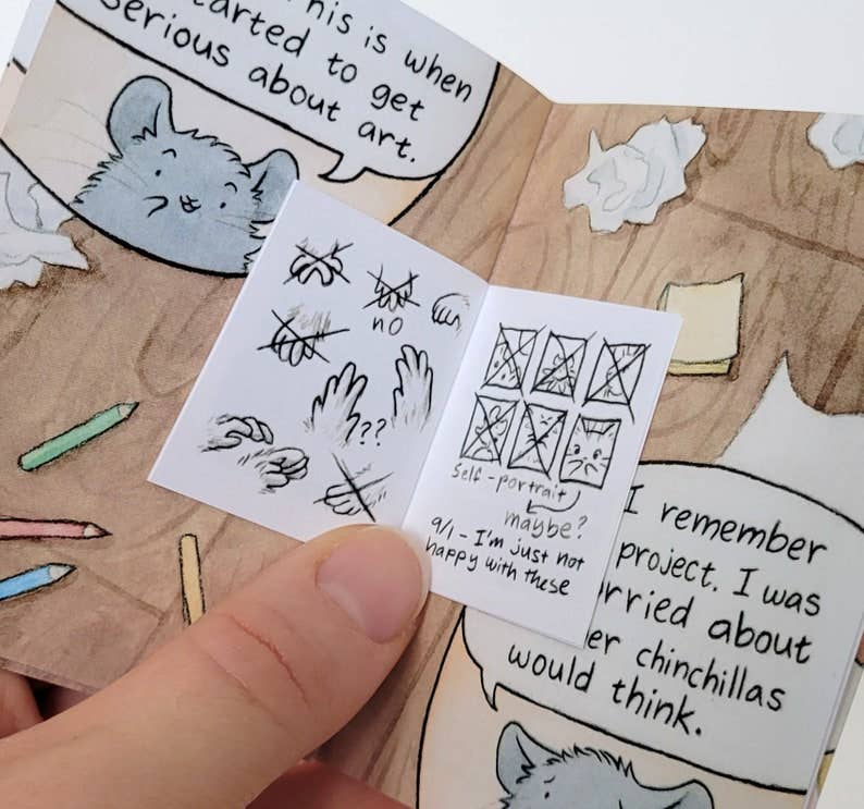 The Chinchillustrator - Mini-Comic Zine with “self-portrait” sketches about artists block held in one hand.