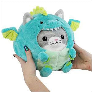 Squishable Undercover Kitty in Dragon, a gray cat plush wearing a blue dragon costume with wings and horns, held in hands.