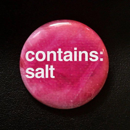 Round, pink 1.25 button pin with white contains: salt text on a black background.