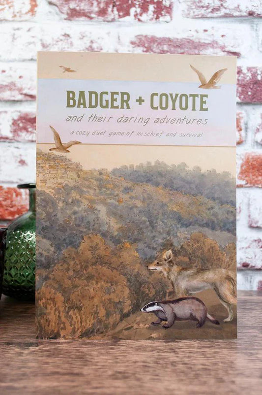 Badger & Coyote greeting card featuring illustrated badger and coyote in a forest with birds above.