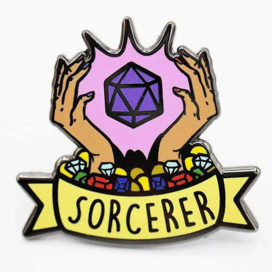 Enamel pin with two hands holding a purple die, gems, and a yellow banner labeled SORCERER.