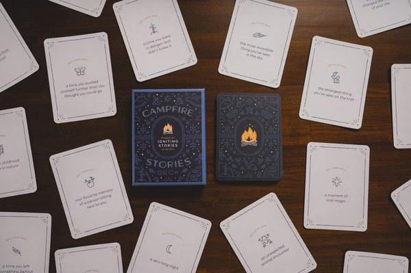 The Campfire Stories Deck Prompts for Igniting Stories with cards displayed on a wooden table.
