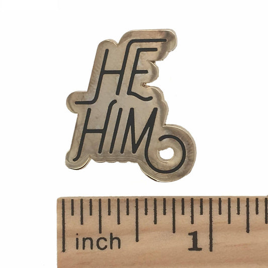 He/Him pronoun silver lapel pin, approximately 1 inch wide, displayed beside a ruler for scale.