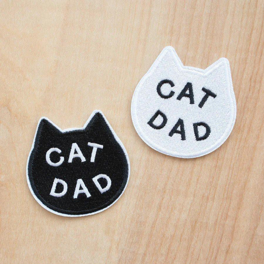 Two embroidered Cat Dad patches in black and white cat shapes, each featuring CAT DAD in bold letters.