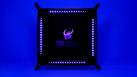 Gen Con 2024 UV Black Light Dice Tray featuring black velvet, purple LED lights, and event logo.