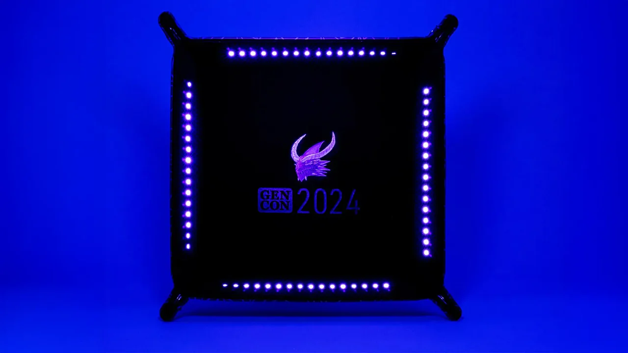 Gen Con 2024 UV Black Light Dice Tray, black and square with a winged logo and blue LED lights.