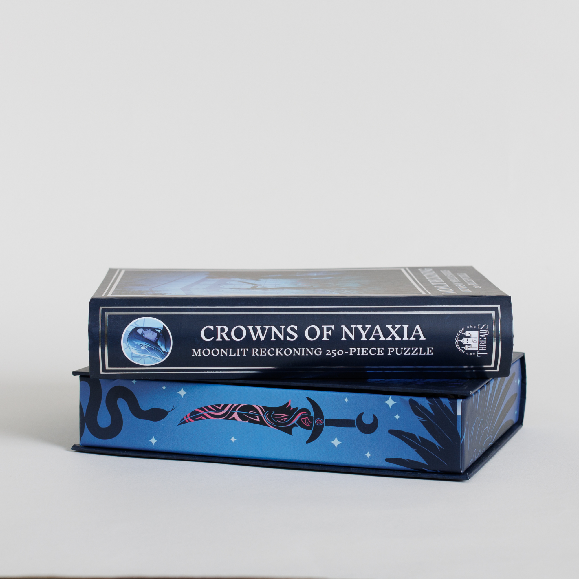 Moonlit Reckoning Keepsake Puzzle | Crowns of Nyaxia blue box stacked on another blue box.