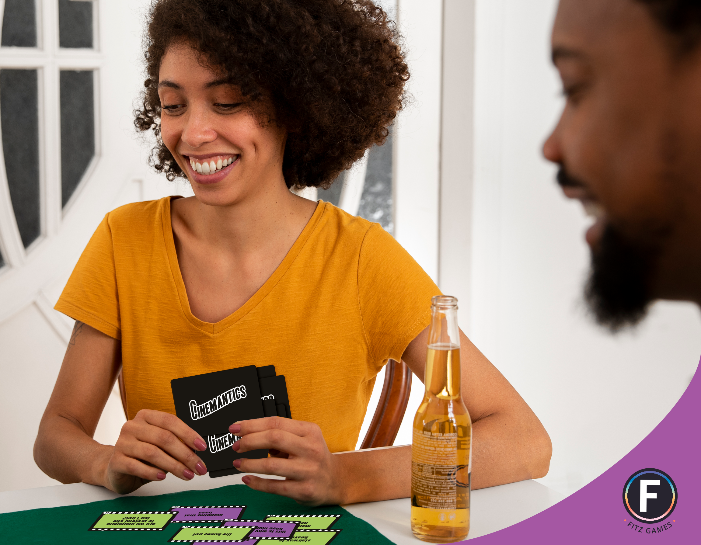 Two people play Cinemantics® at a table with a drink beside them.