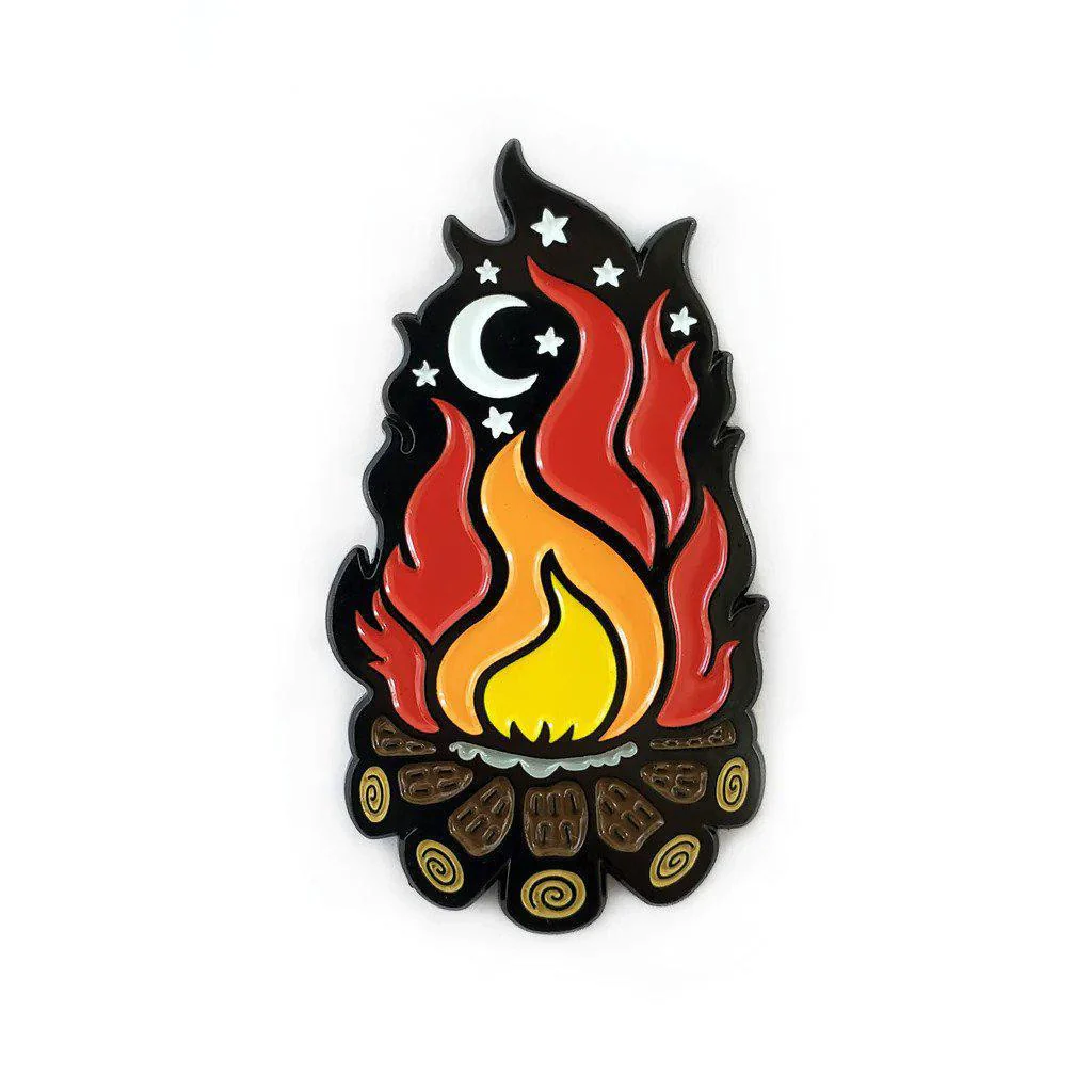 Campfire enamel pin with red and yellow flames, logs, stars, and crescent moon on white background.