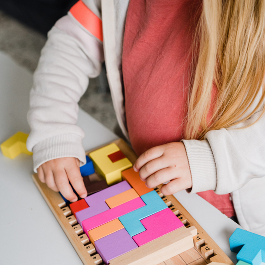 Katamino Family wooden puzzle game with colorful geometric pieces and progressive difficulty shown in use by a child.