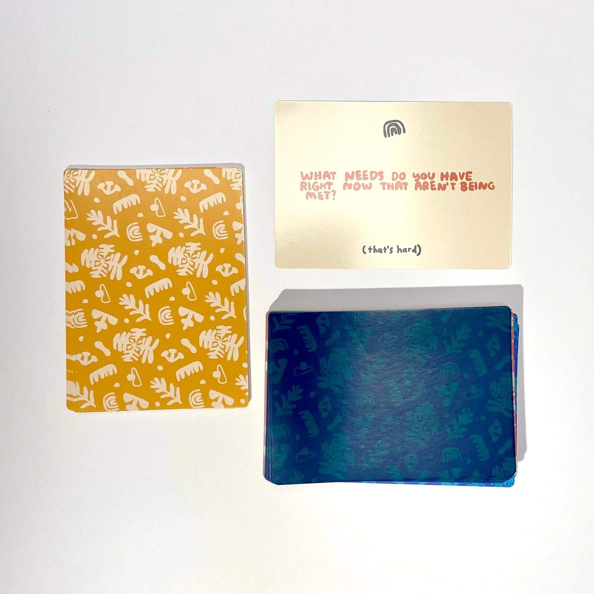 A Safe Space For Us Deck showing three cards: yellow, blue pattern, and a relationship prompts card about unmet needs.