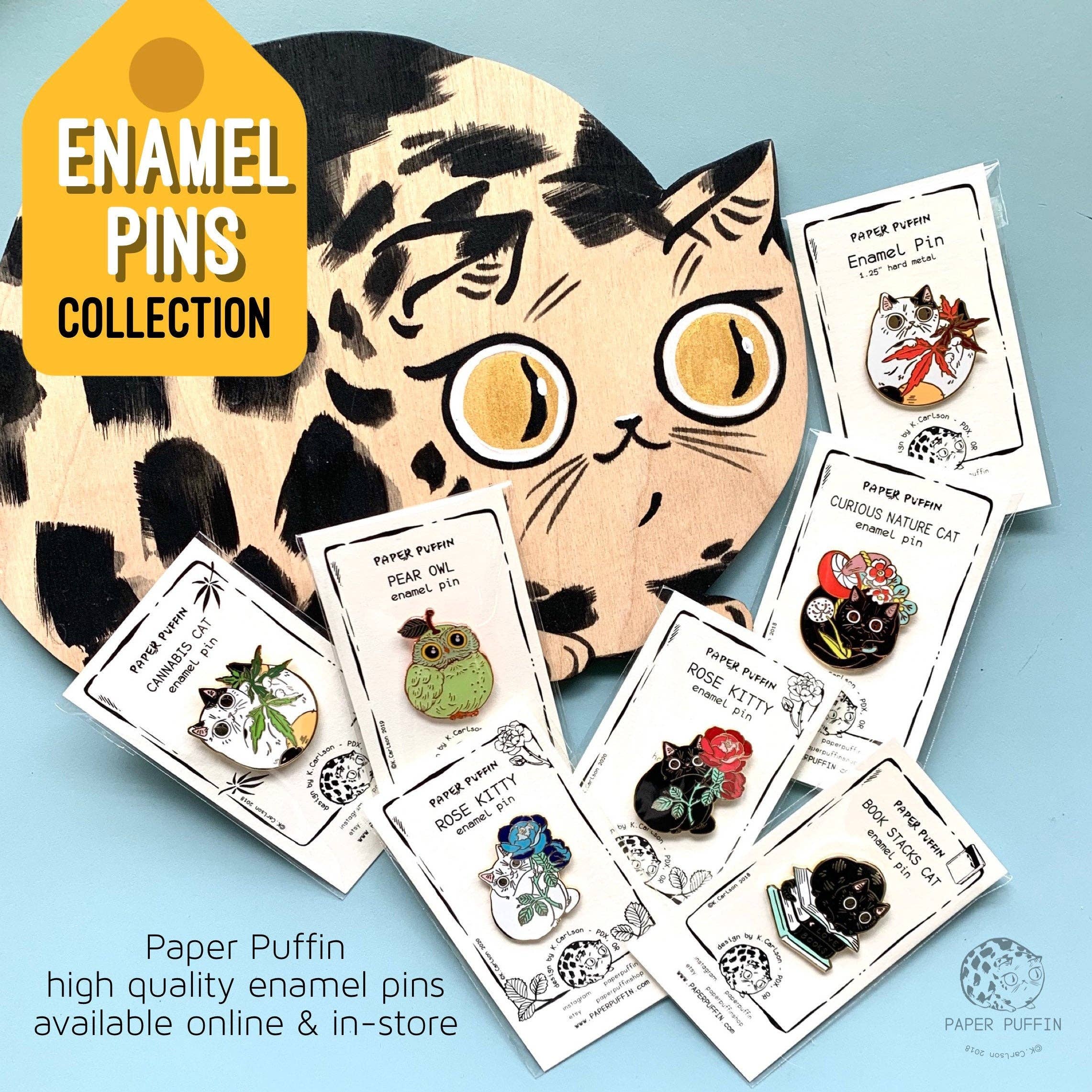 Six enamel pins, including a Book Stacks Cat Enamel Pin.