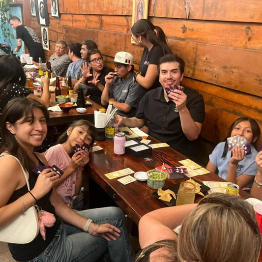 People play Roast: A Game of Sinister Sweetness and Cozy Betrayal at a restaurant table.