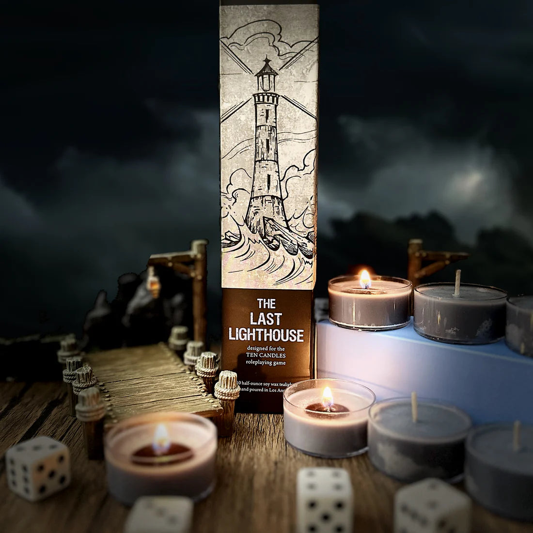 The Last Lighthouse box with Ten Candles: Cryptid Cabin Tea Candles, dice, and wooden pier nearby.