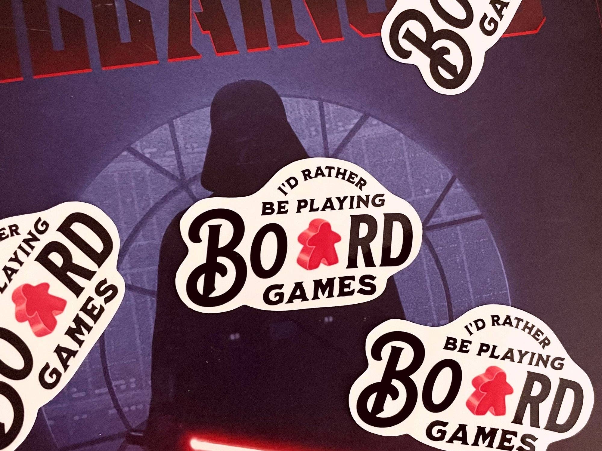 Id Rather Be Playing Board Games Sticker with a helmeted, caped meeple on a dark background.