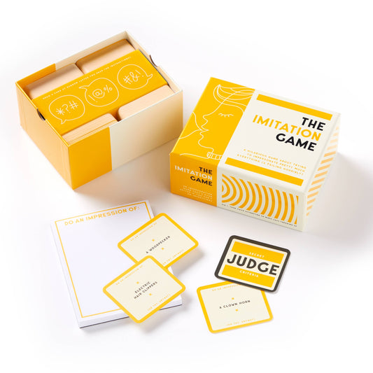The Imitation Game set with cards and notepad in yellow-white packaging on a white surface.
