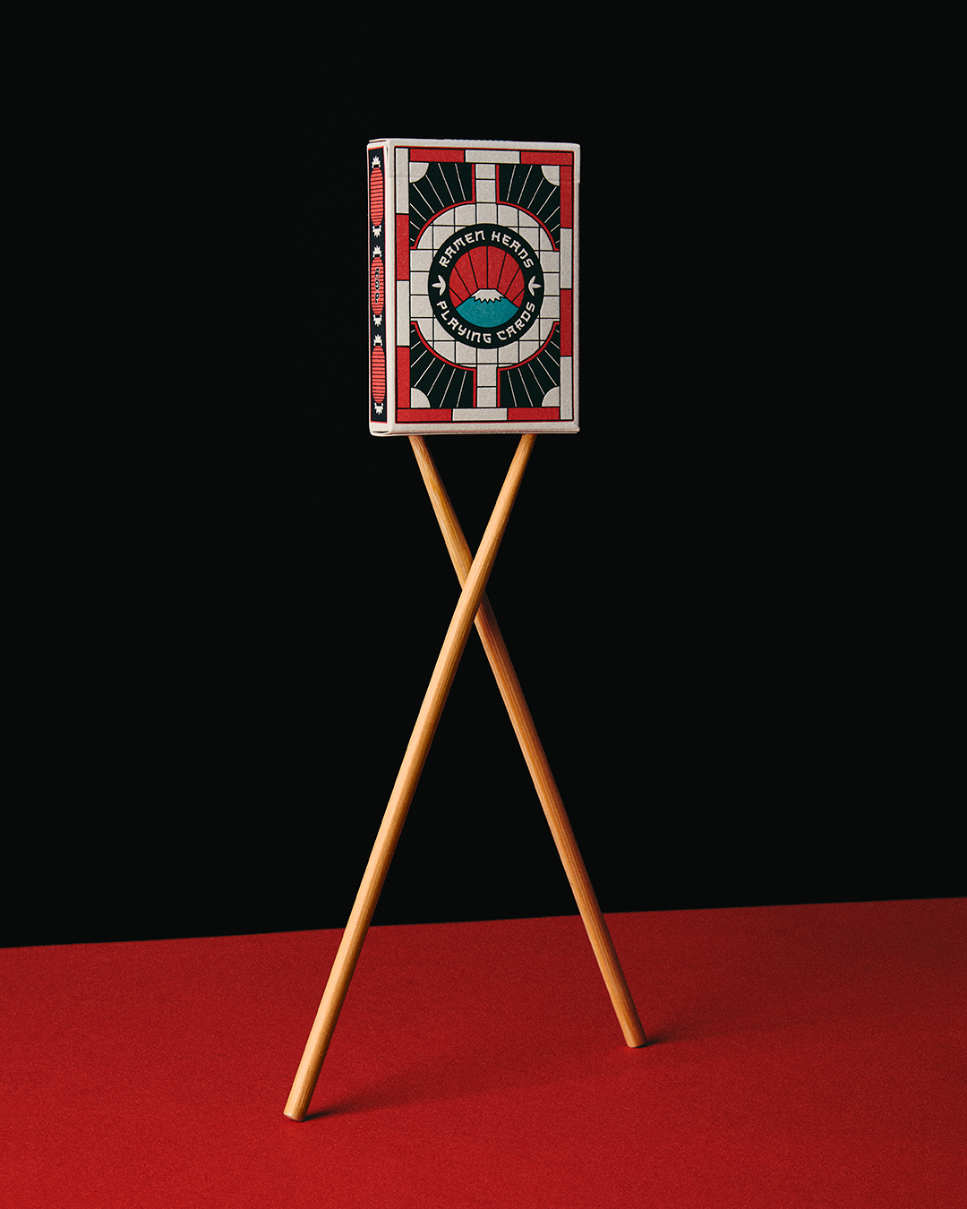 Ramen Heads playing cards balanced on two crossed wooden chopsticks.