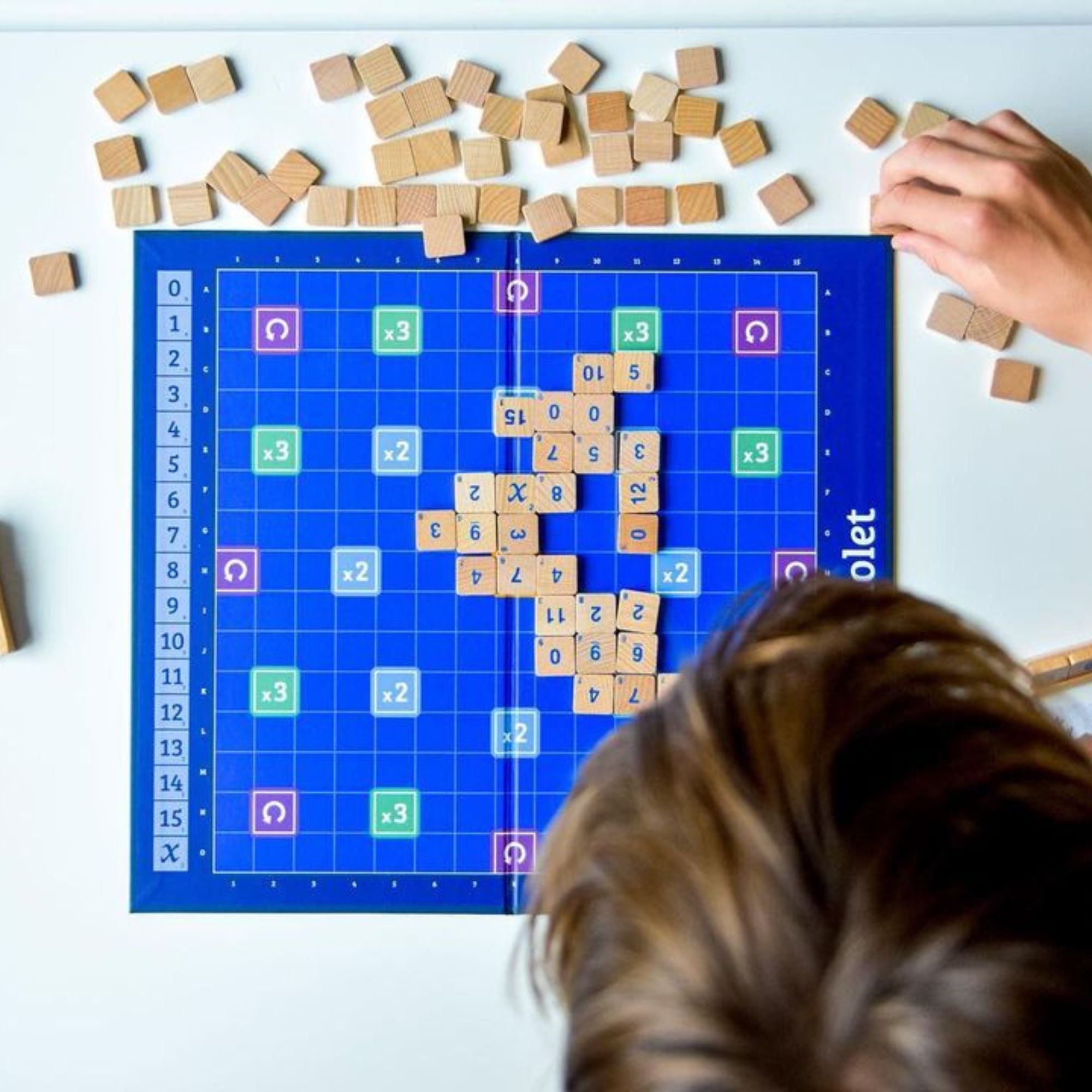 Triolet tile board game with wooden tiles on blue game board, shown from above.