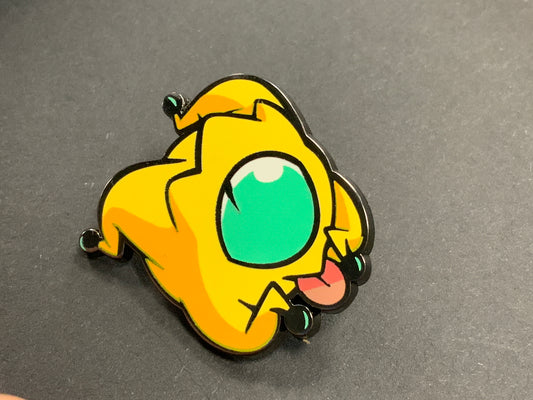 Heliana monster hunting pin Peeper with a yellow star, green eye, and tongue out on a dark background.