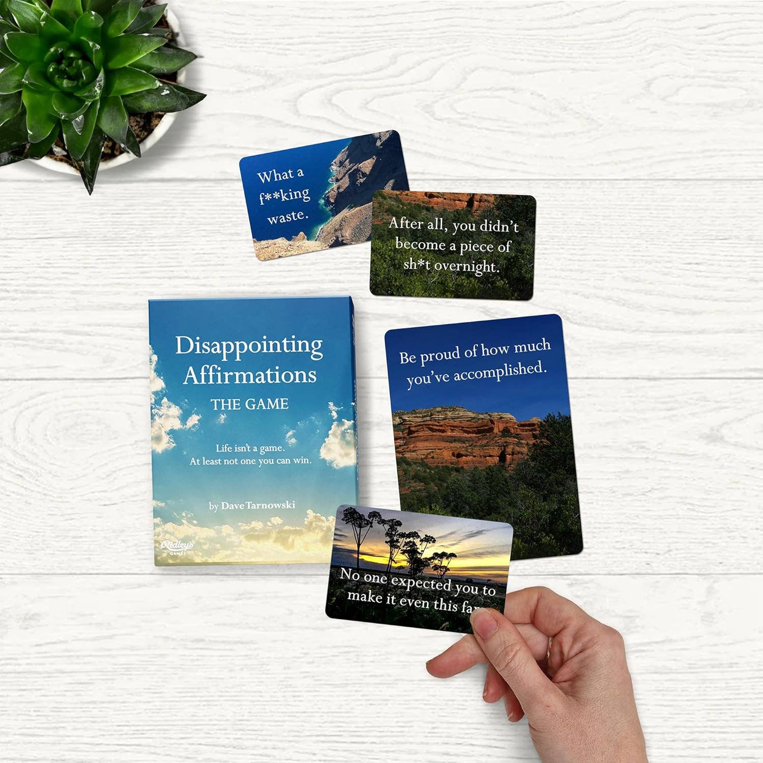 Disappointing Affirmations: The Disappointing Game cards held in a hand and spread on a table.