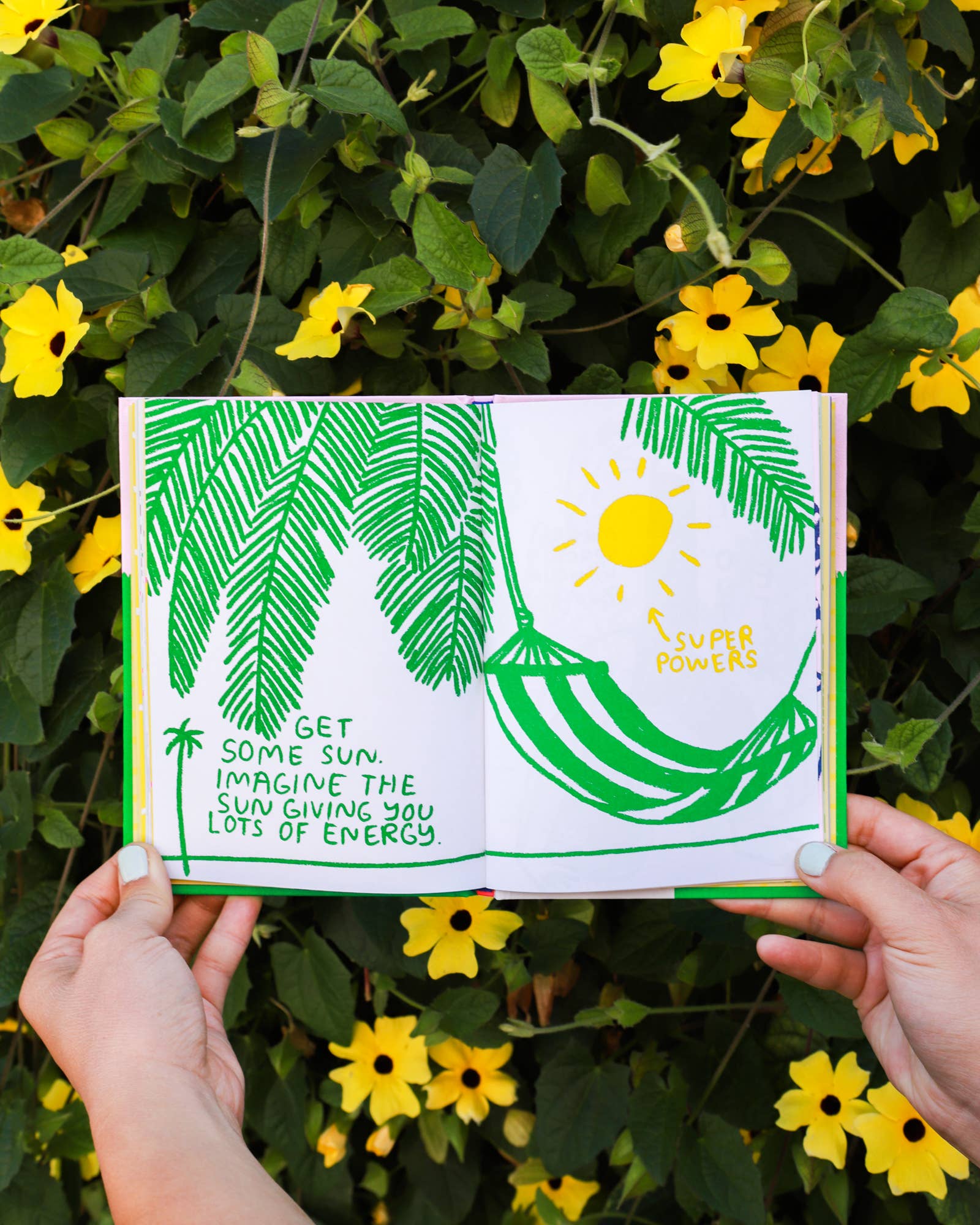 Person holding Its OK to Feel Things Deeply journal with yellow flowers in the background.
