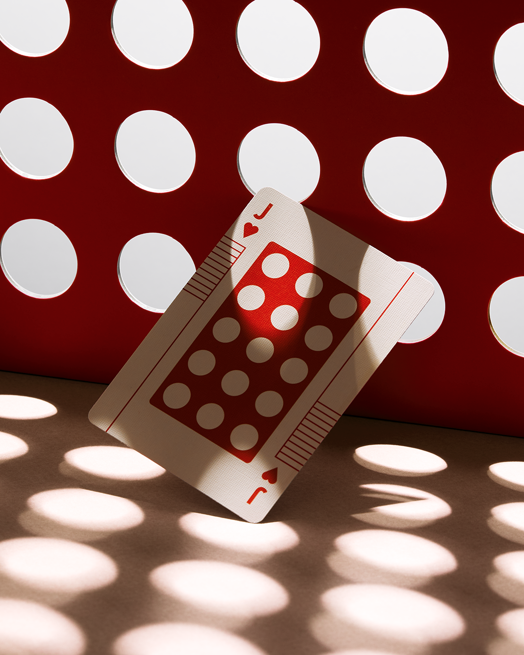 Eames The Little Toy Jack of Hearts playing card with red circular pattern on a matching red panel.