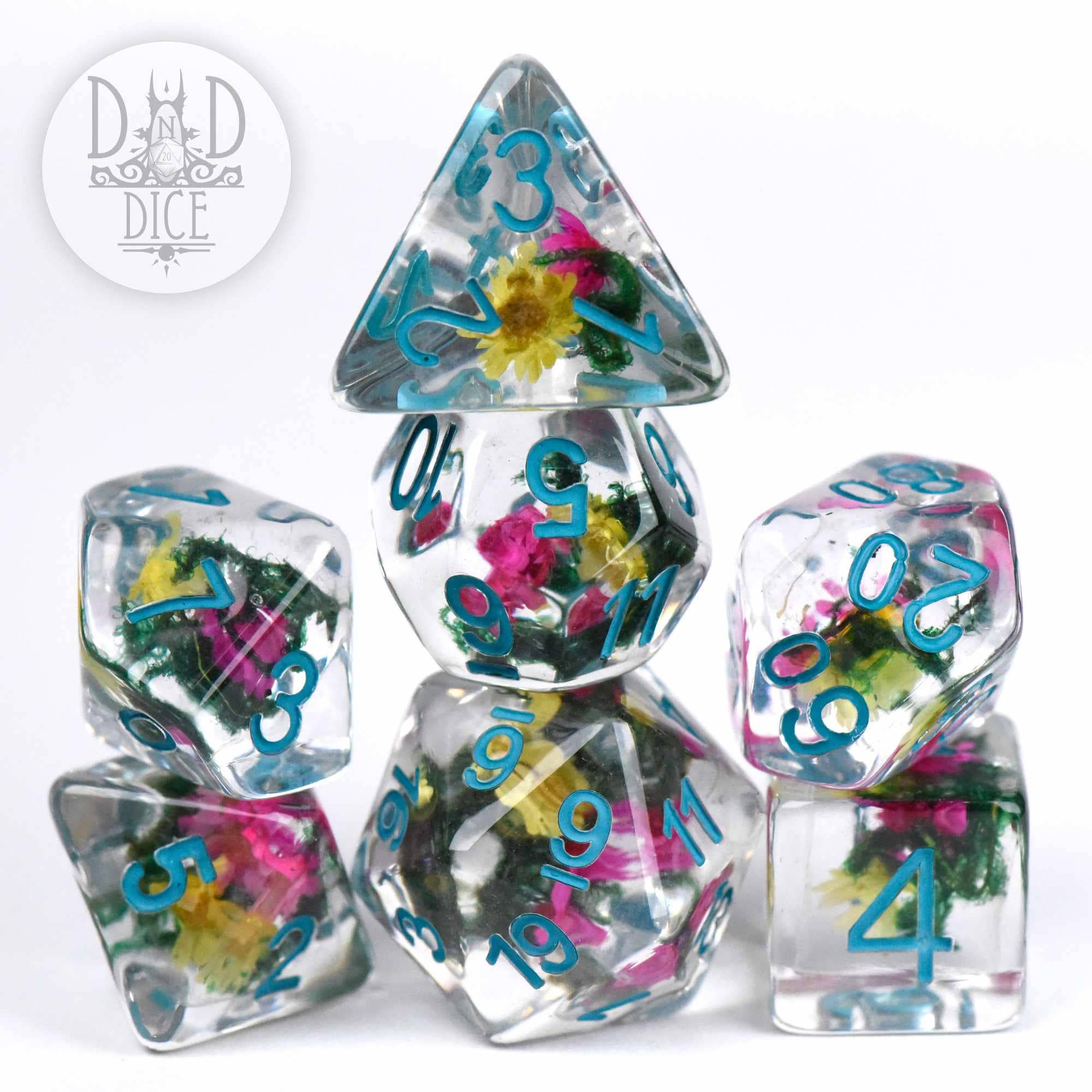 Vintage Bloom clear resin D&D dice set with embedded colorful flowers and blue numbers, stacked in a pyramid.