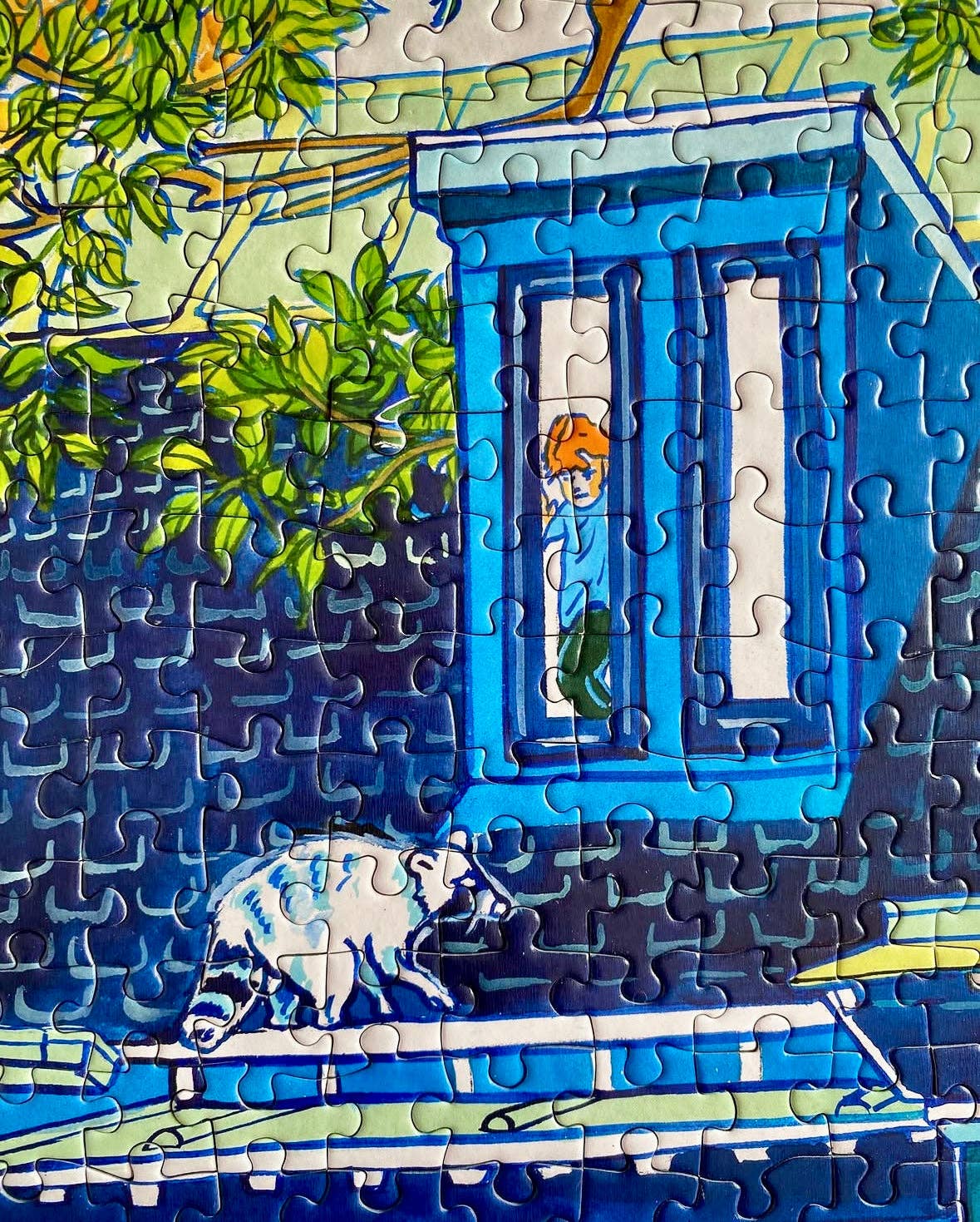 City Culture 1000-piece puzzle featuring art by Jules Monson with a raccoon on a blue roof and a child above.