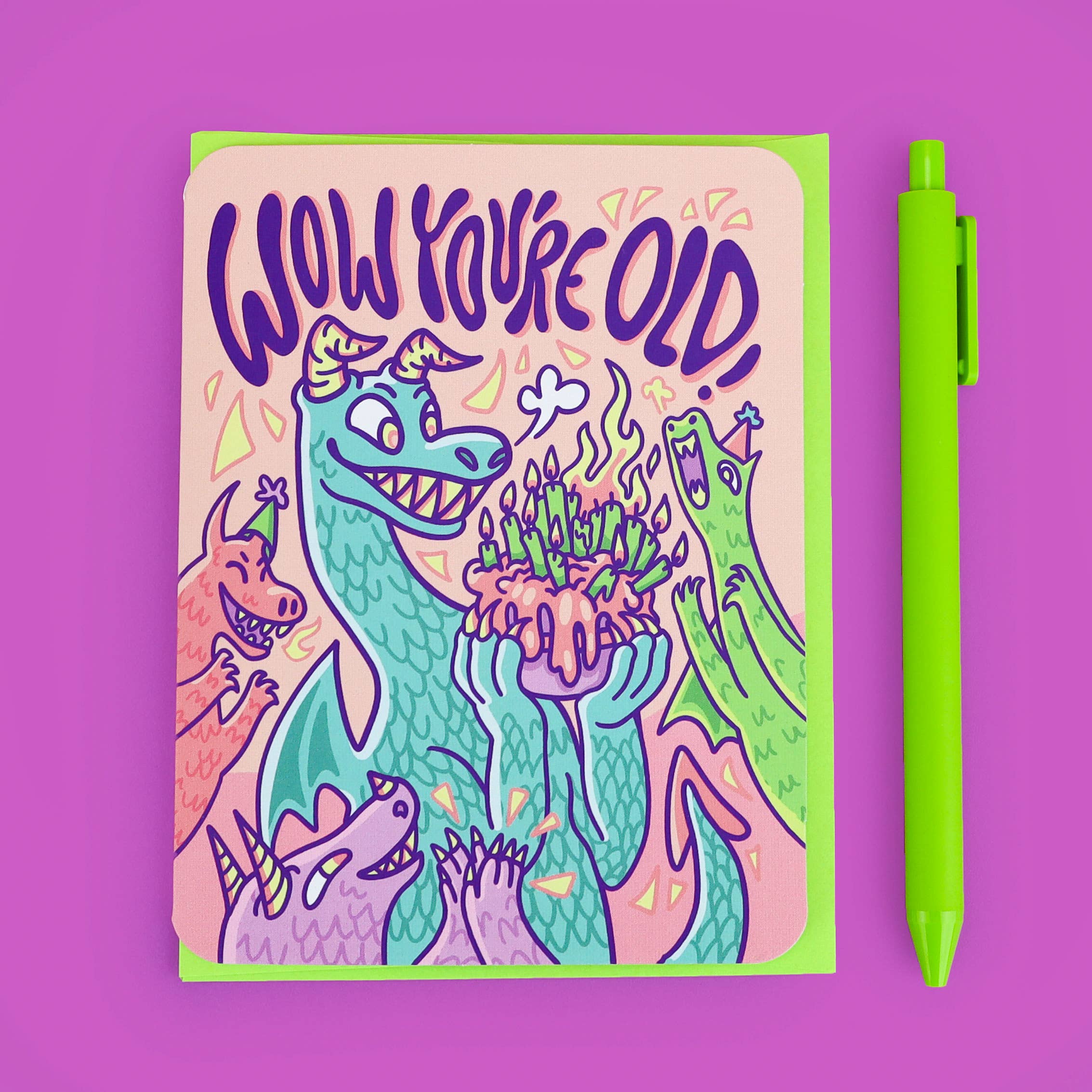 Wow Youre Old dragon birthday card with cartoon dragons, cake, and humorous text; green pen next to card.