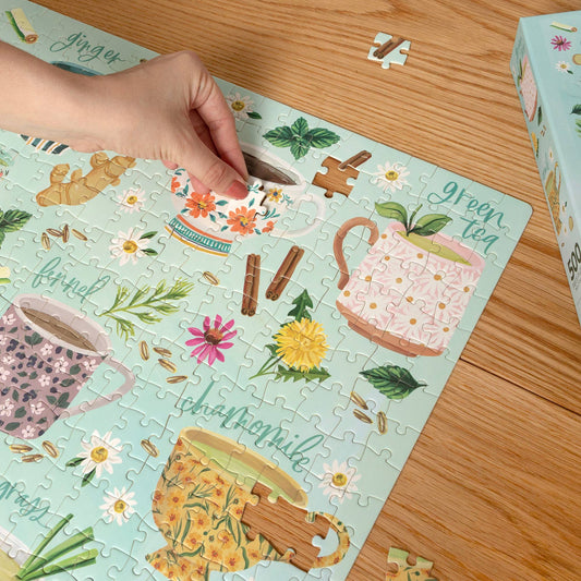 A hand places a piece in the Tea Time 500 Piece Jigsaw Puzzle.