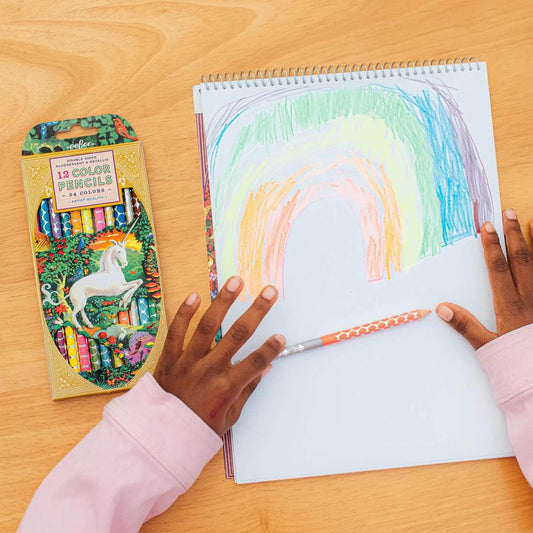 Unicorn Garden 12 Double Color Pencils set on table next to a child drawing a rainbow.