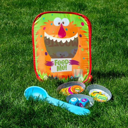 Giant Feed The Woozle game with colorful target, “Feed Me” sign, includes balls, frisbees, and scoop.