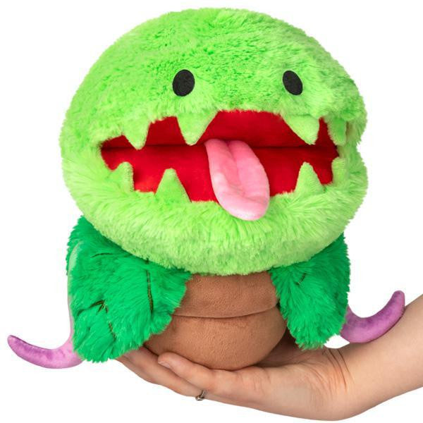Mini Venus Fly Trap plush toy with green body, magnetic mouth, red tongue, and purple tentacles held in a hand.