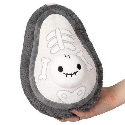 Squishables Alter Ego Avocado-Skeleton, a gray plush avocado toy with skeleton design, held in a hand.