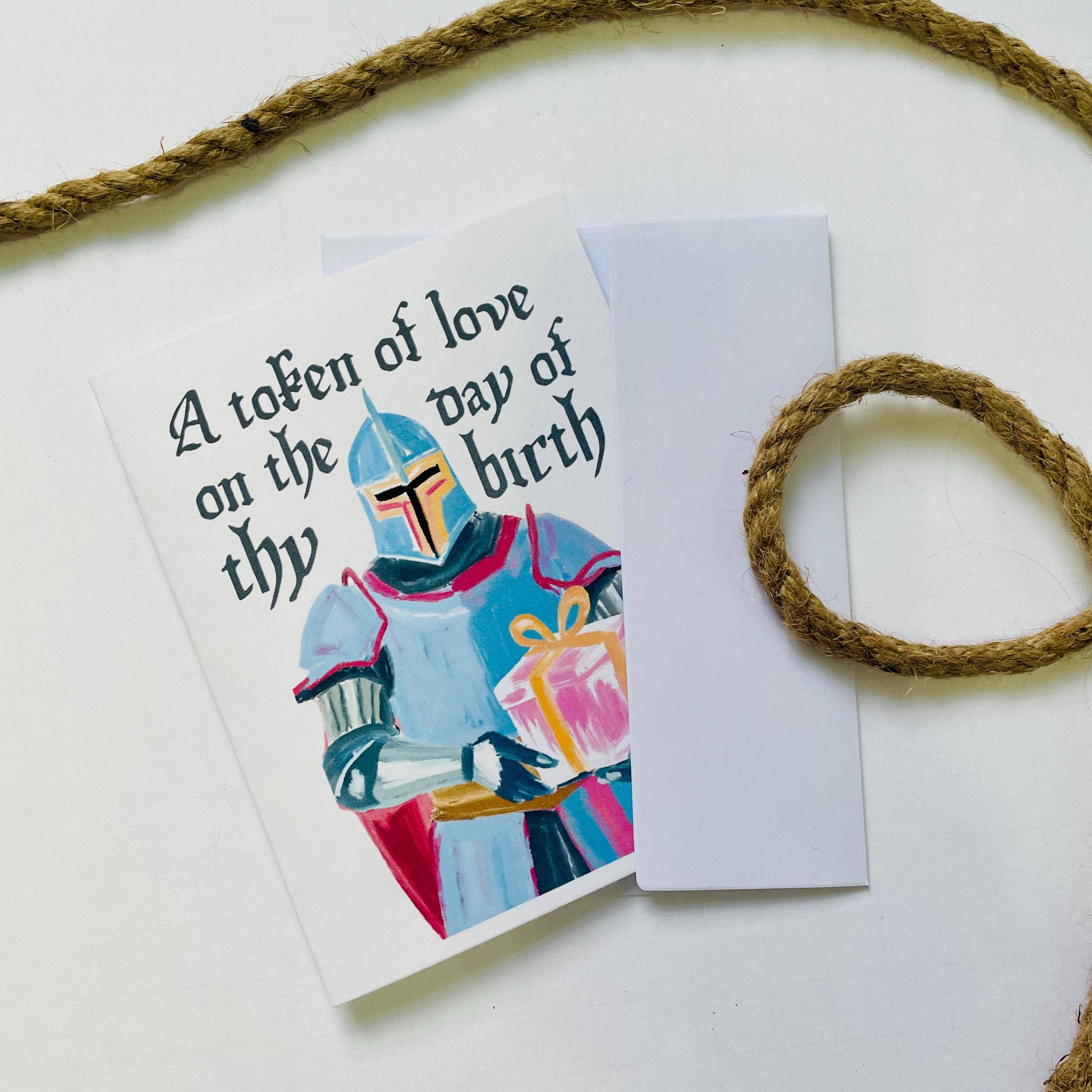 Birthday card featuring an armored knight holding a gift, with the text A token of love on thy birth.