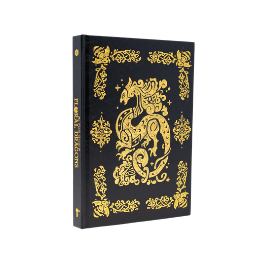 The Field Guide To Floral Dragons deluxe hardcover with gold dragon designs on a black cover.