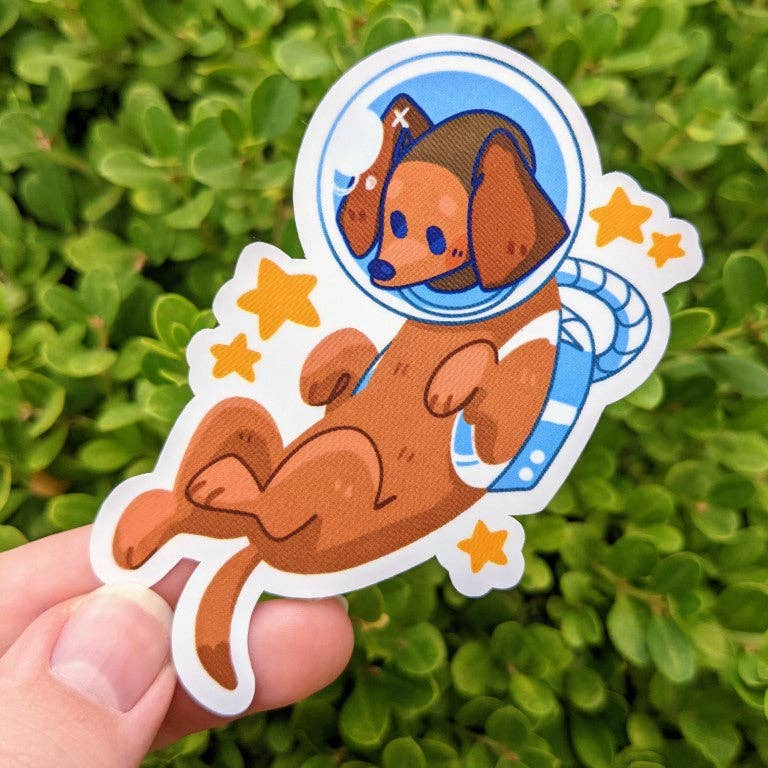 Halloween Puppies Stickers pack with cartoon dachshund in a spacesuit, stars, and green leaves held in a hand.