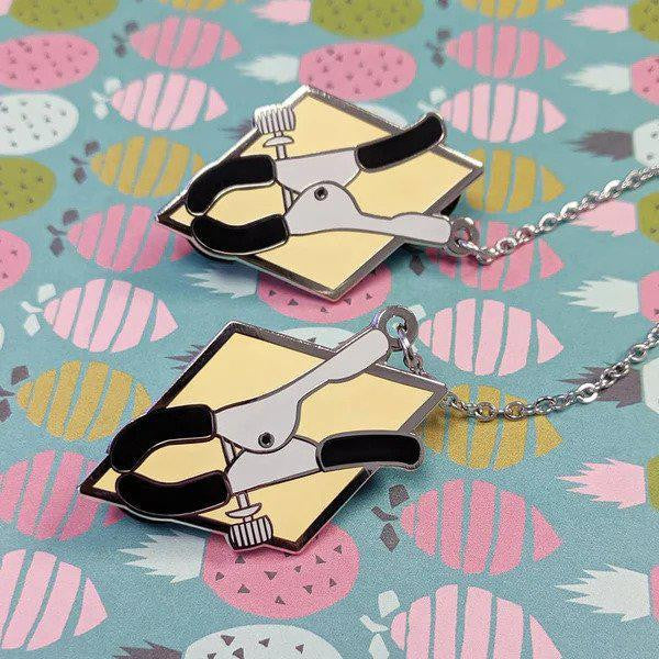 Clamps hard enamel collar pin set with two black plier pins on a yellow background.
