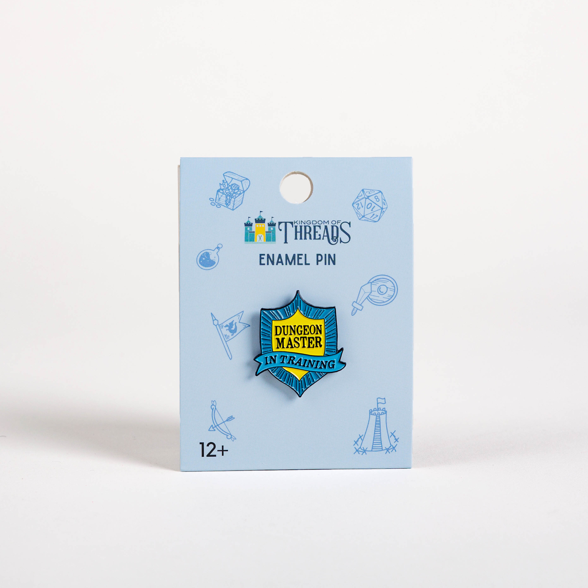 Blue and yellow Dungeon Master in Training Badge enamel pin on a blue card labeled Enamel Pin.