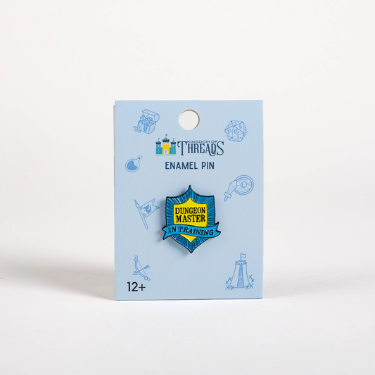 Blue and yellow Dungeon Master in Training Badge enamel pin on a blue card labeled Enamel Pin.