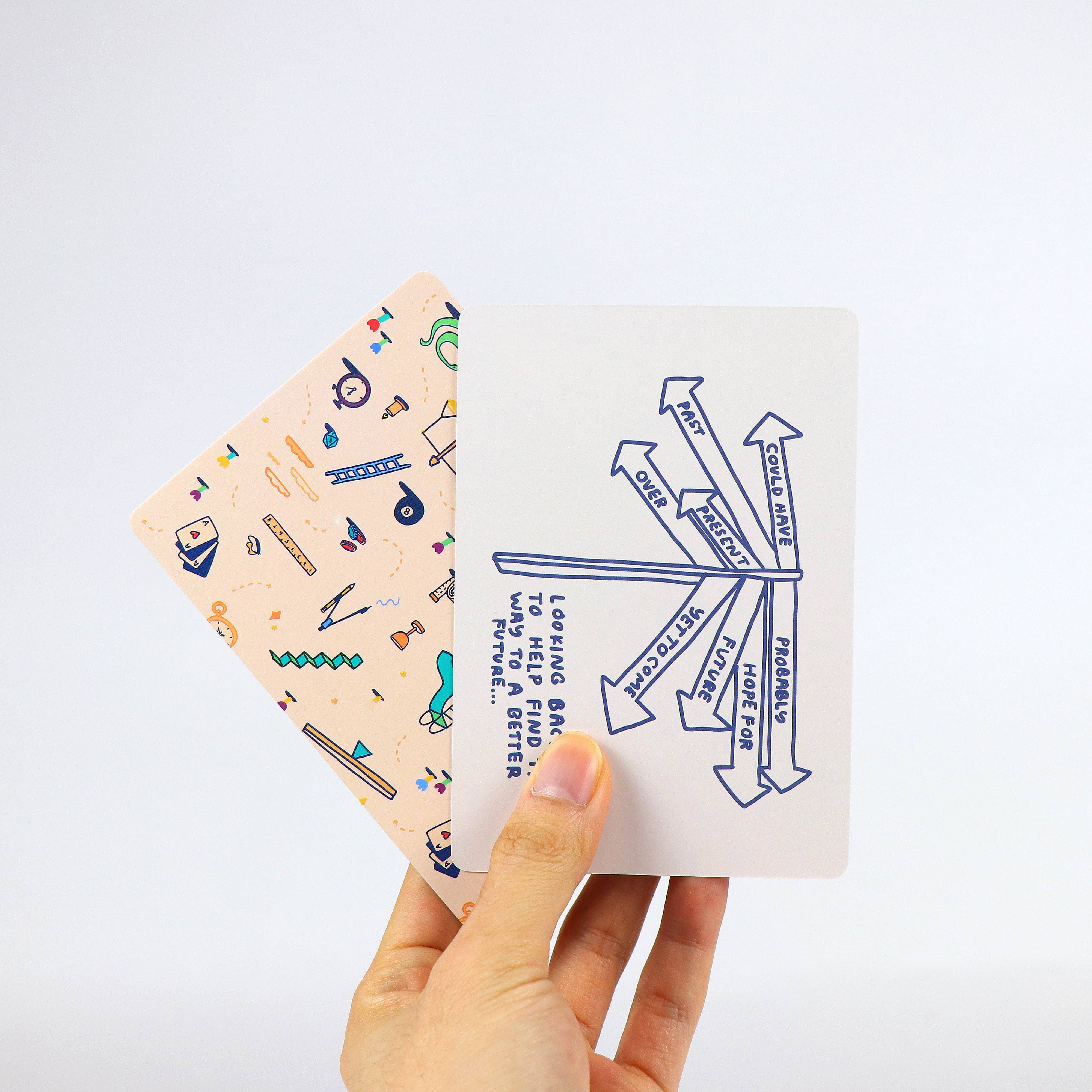 Two How To Decide Deck cards held in a hand; one shows blue arrows and text, the other has abstract colorful patterns.