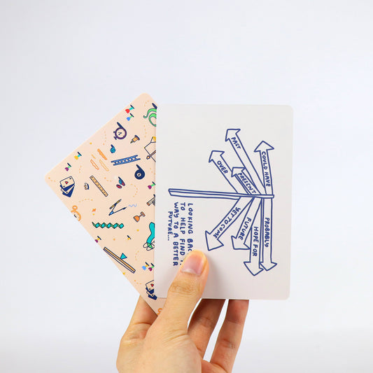 Two How To Decide Deck cards held in a hand; one shows blue arrows and text, the other has abstract colorful patterns.