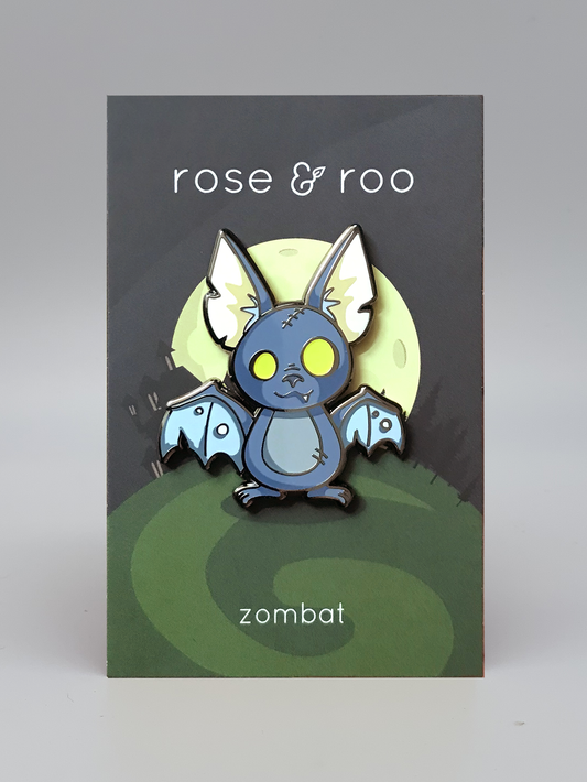 Zombat Bat Enamel Pin (Glow-in-the-Dark) with bright yellow eyes, shown on a rose & roo zombat card.