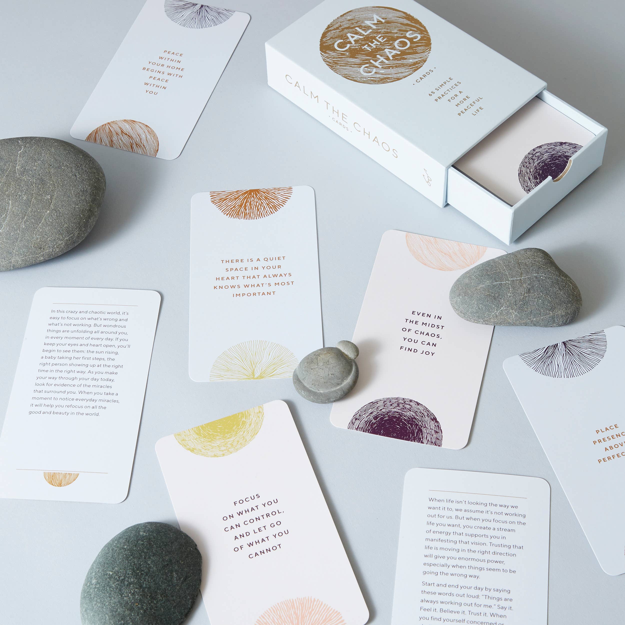 Calm the Chaos Cards with motivational quotes, a box, and smooth stones.